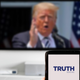 Truth Social logo displayed on a smartphone against blurred background with Trump on TV